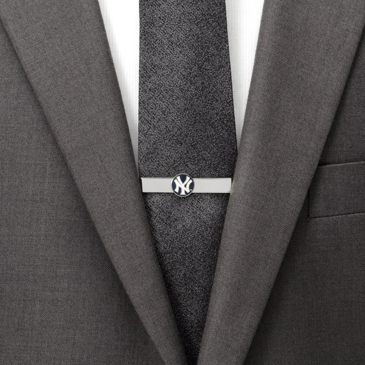 A silver, officially licensed MLB New York Yankees Tie Bar clipped to a dark textured tie and gray suit jacket.
