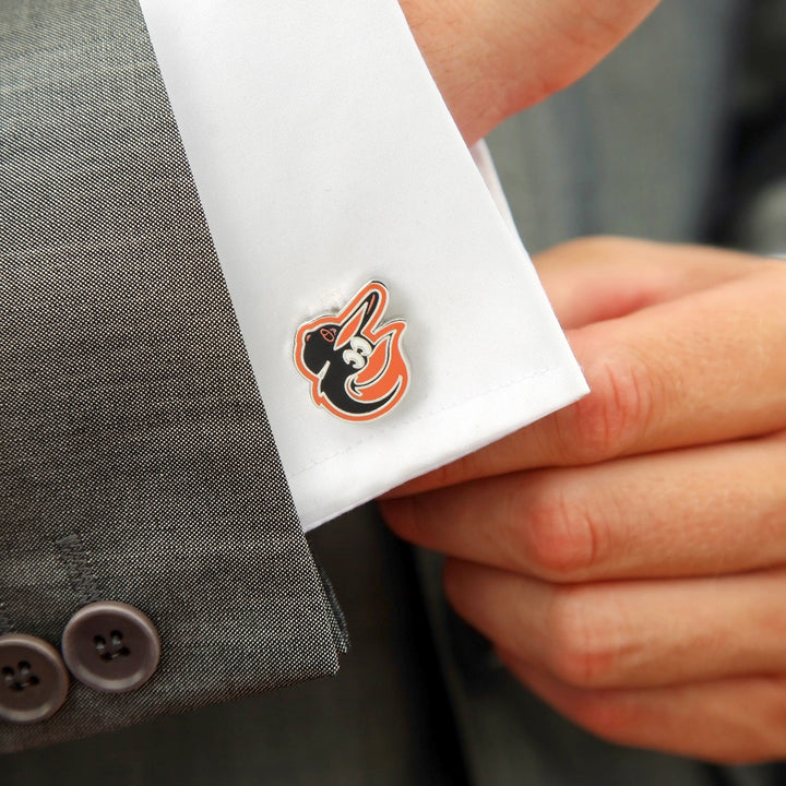 A person adjusts a white shirt cuff featuring MLB Baltimore Orioles Cufflinks, currently available as a final sale item.