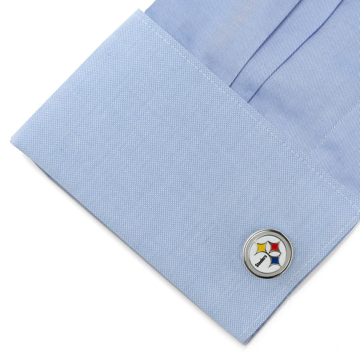 A circular silver NFL Pittsburgh Steelers Cufflinks attached to a light blue dress shirt cuff.
