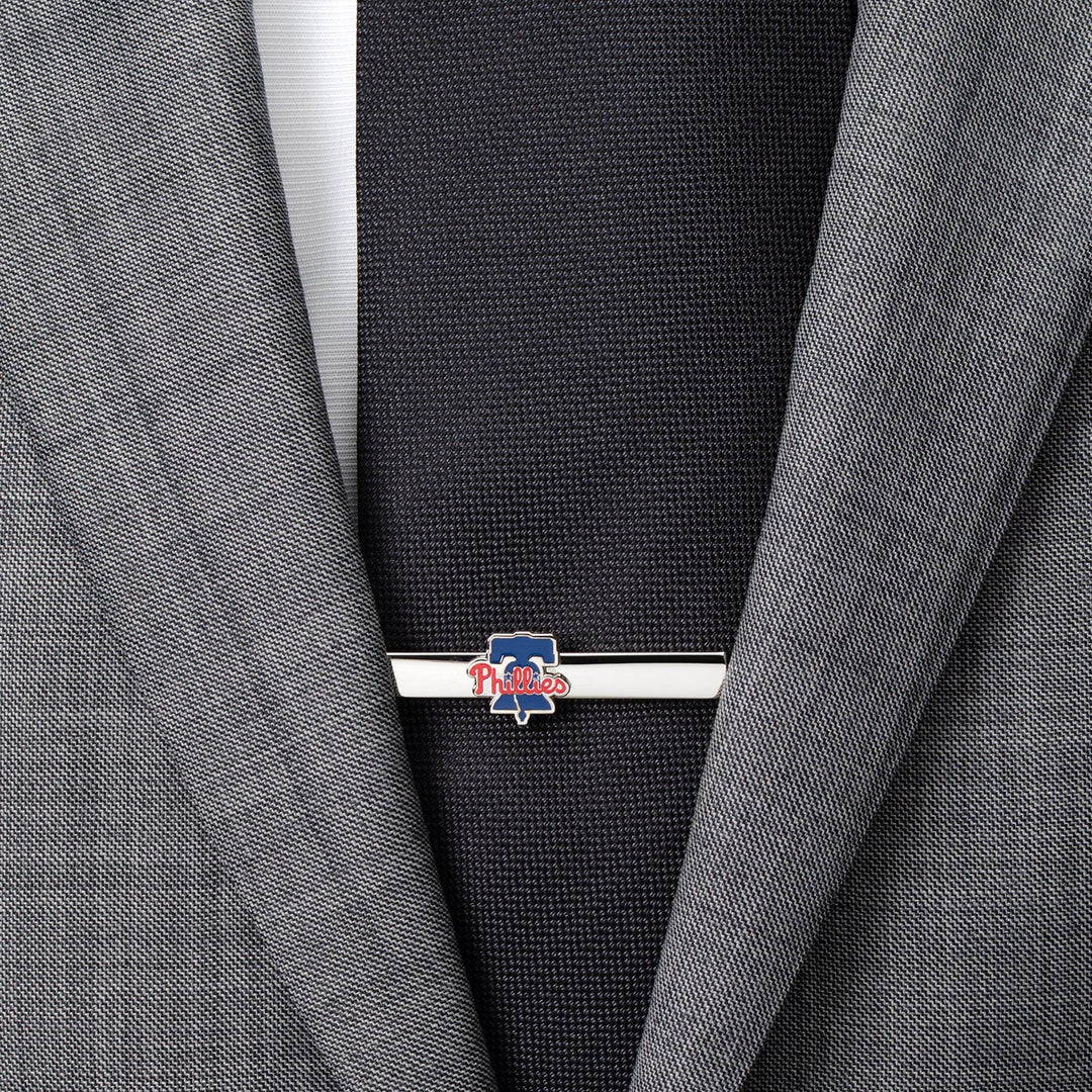 A silver-toned Philadelphia Phillies Tie Clip fastened to a black tie and grey suit jacket.