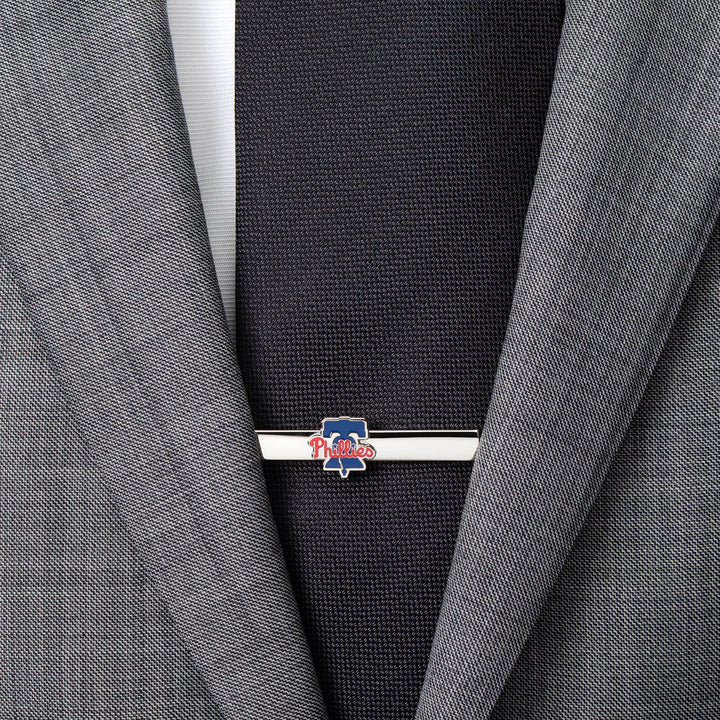 A silver-toned Philadelphia Phillies Tie Clip fastened to a black tie and grey suit jacket.