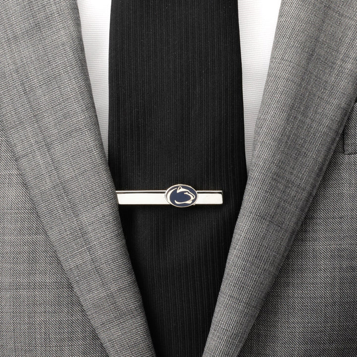 Silver NCAA Penn State University Nittany Lions Tie Clip featuring a blue and white mountain lion head logo, attached to a black tie and grey suit jacket.