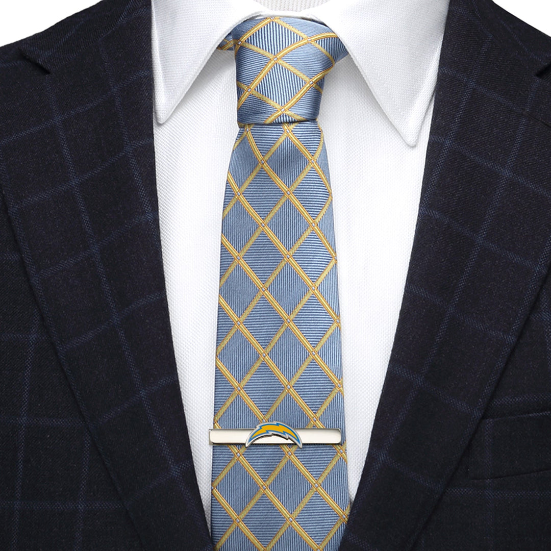 A silver-plated NFL Los Angeles Chargers Tie Clip shaped like a lightning bolt, fastened to a blue and yellow grid-patterned tie worn with a white shirt and dark blazer.