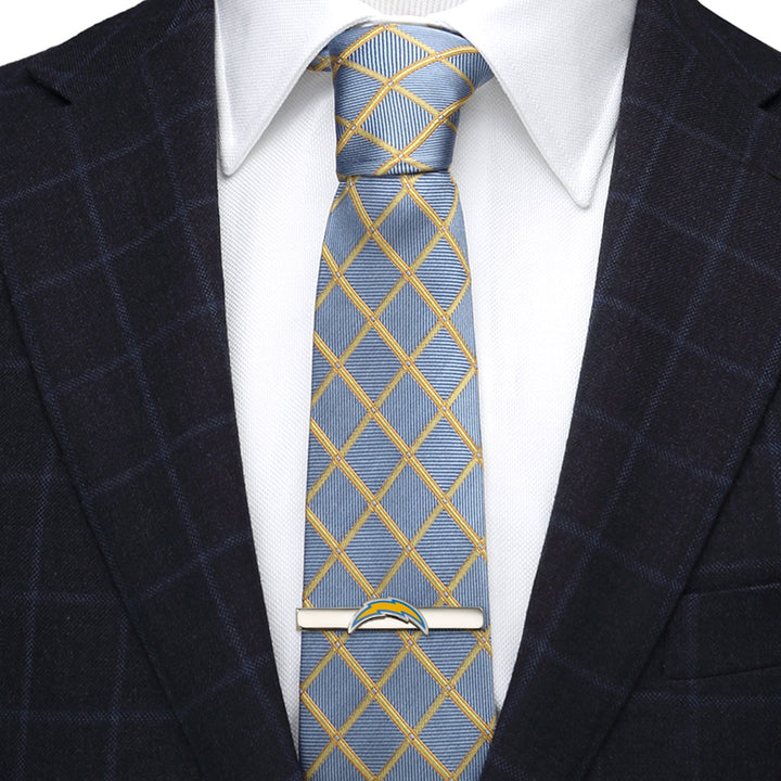 A silver-plated NFL Los Angeles Chargers Tie Clip shaped like a lightning bolt, fastened to a blue and yellow grid-patterned tie worn with a white shirt and dark blazer.