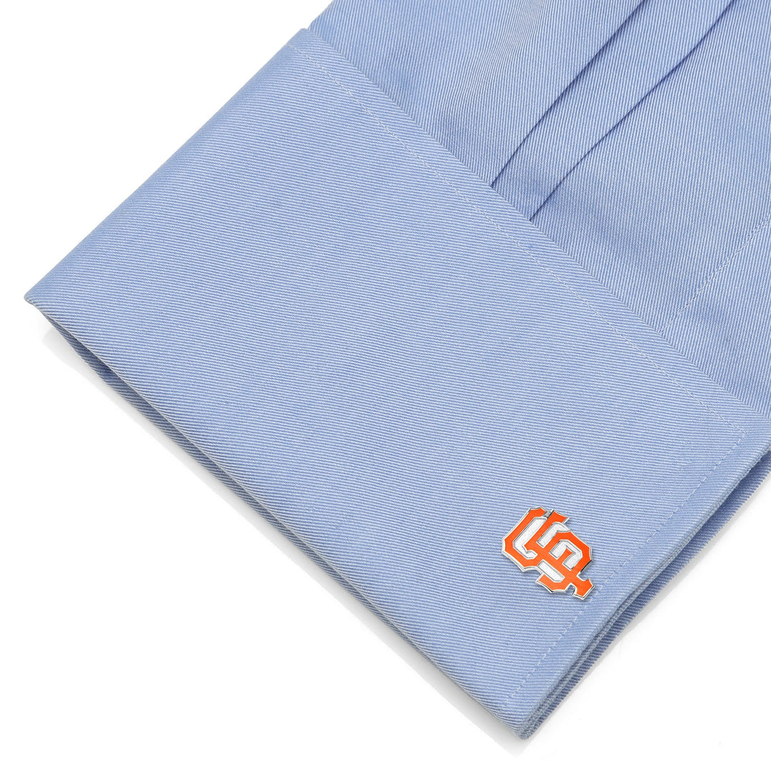 Orange and cream-colored MLB San Francisco Giants Cufflinks attached to a light blue dress shirt cuff.