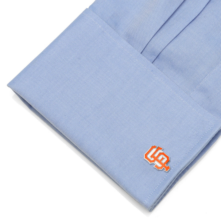 Orange and cream-colored MLB San Francisco Giants Cufflinks attached to a light blue dress shirt cuff.