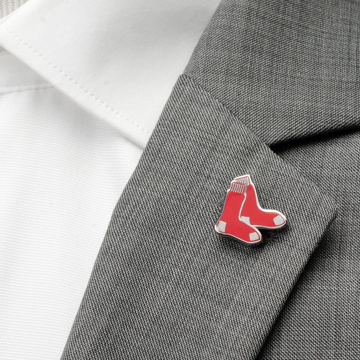 An MLB Boston Red Sox Lapel Pin shaped like a pair of red socks fastened to the lapel of a gray suit jacket.