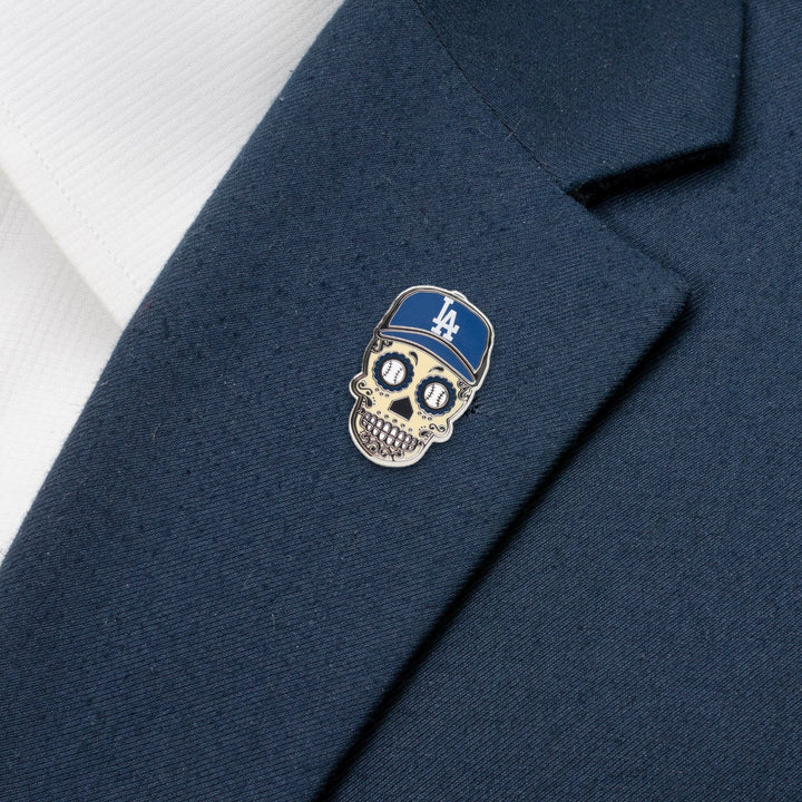 A MLB LA Dodgers Sugar Skull Lapel Pin featuring a blue LA Dodgers baseball cap, attached to the lapel of a navy blue blazer.