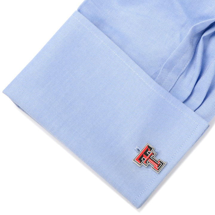 A silver NCAA Texas Tech University Red Raiders cufflink fastened to a light blue dress shirt cuff.