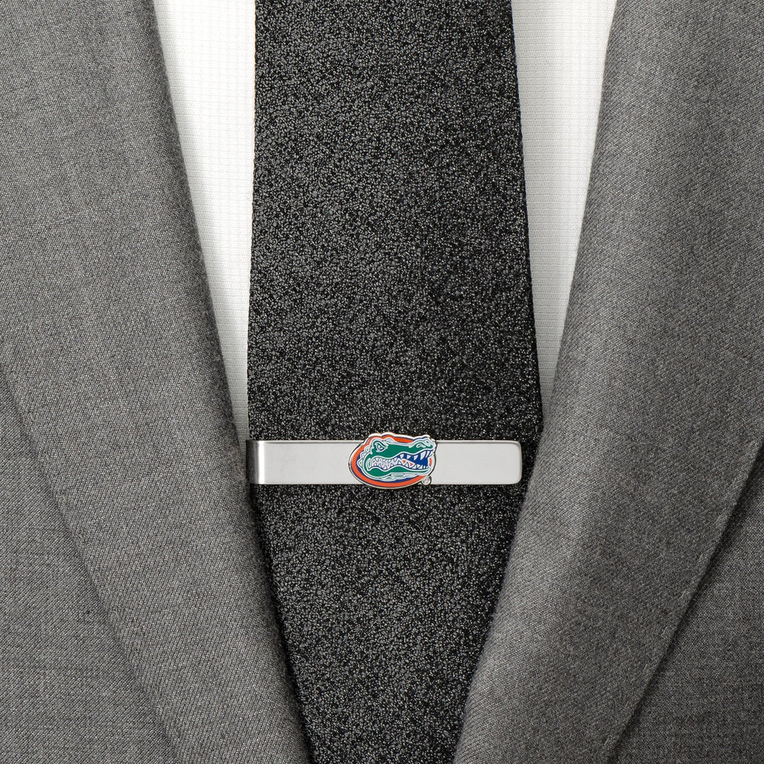 A silver NCAA University of Florida Gators Tie Bar clipped to a textured black tie worn with a grey suit jacket.
