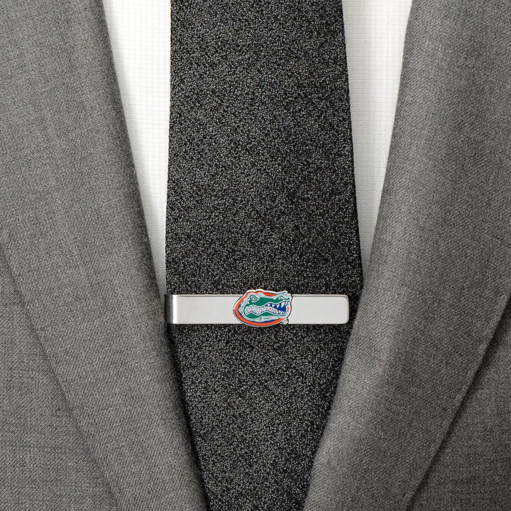 A silver NCAA University of Florida Gators Tie Bar clipped to a textured black tie worn with a grey suit jacket.