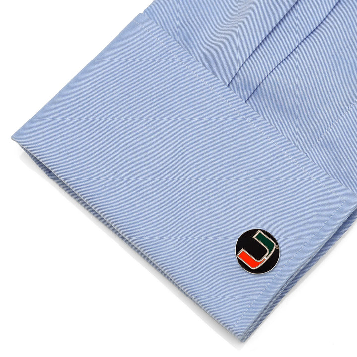 Round NCAA Miami Hurricanes Cufflinks featuring the green, orange, and white “U” logo, fastened to a light blue dress shirt cuff.