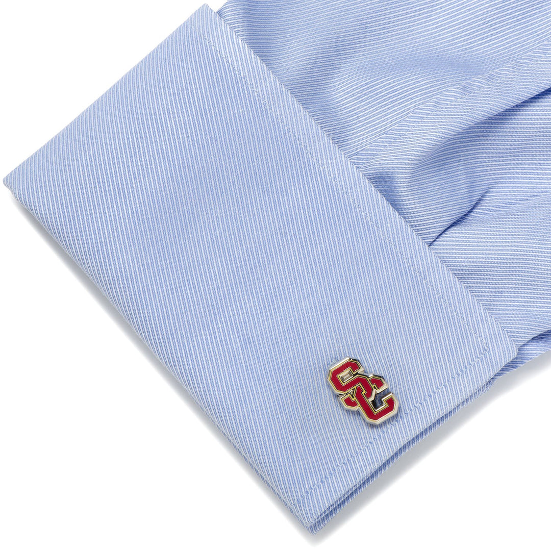 NCAA University of Southern California Trojans cufflinks featuring a silver finish and a red and gold interlocking logo on a light blue dress shirt cuff.