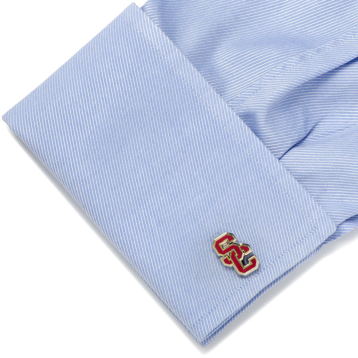 NCAA University of Southern California Trojans cufflinks featuring a silver finish and a red and gold interlocking logo on a light blue dress shirt cuff.