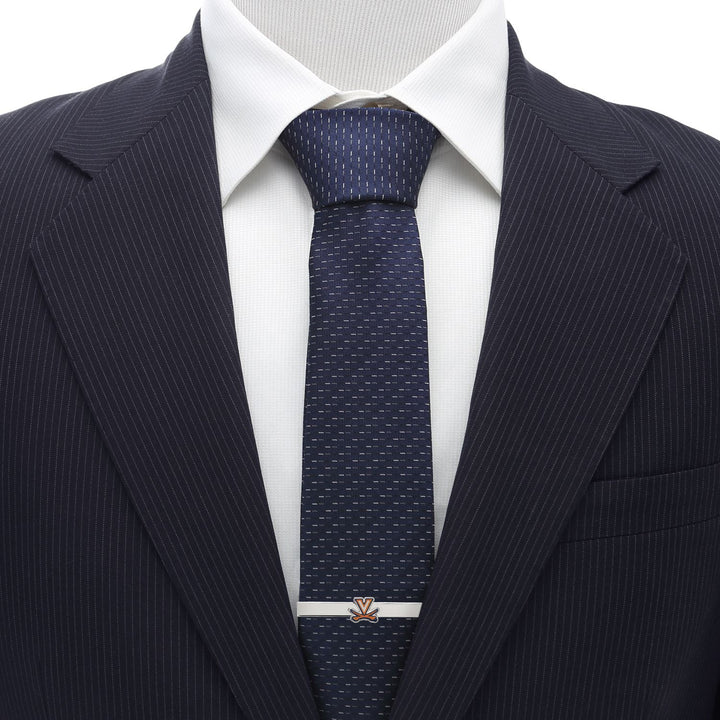 An NCAA University of Virginia Cavaliers Tie Clip with an orange and blue collegiate “V” logo on a dark blue patterned tie, white shirt, and pinstripe suit jacket.