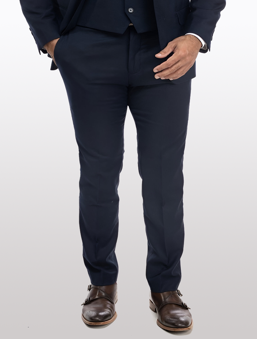 A person wearing Karako Separate Navy Men's Slim-Fit Suit Separates Pants and brown dress shoes stands with one hand in their pocket against a plain background.