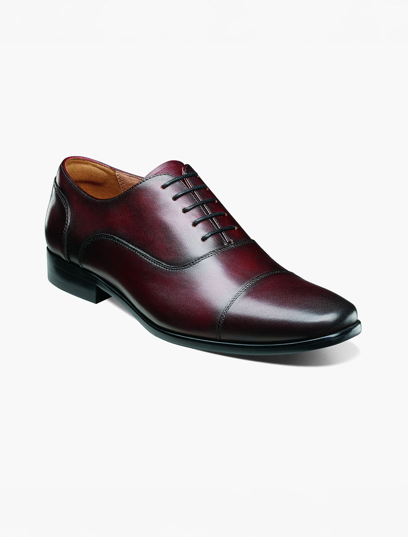 The Florsheim Wine Cap Toe Oxford Shoe is shown on a white background, featuring black laces, Flexsole Technology, and a cushioned footbed.