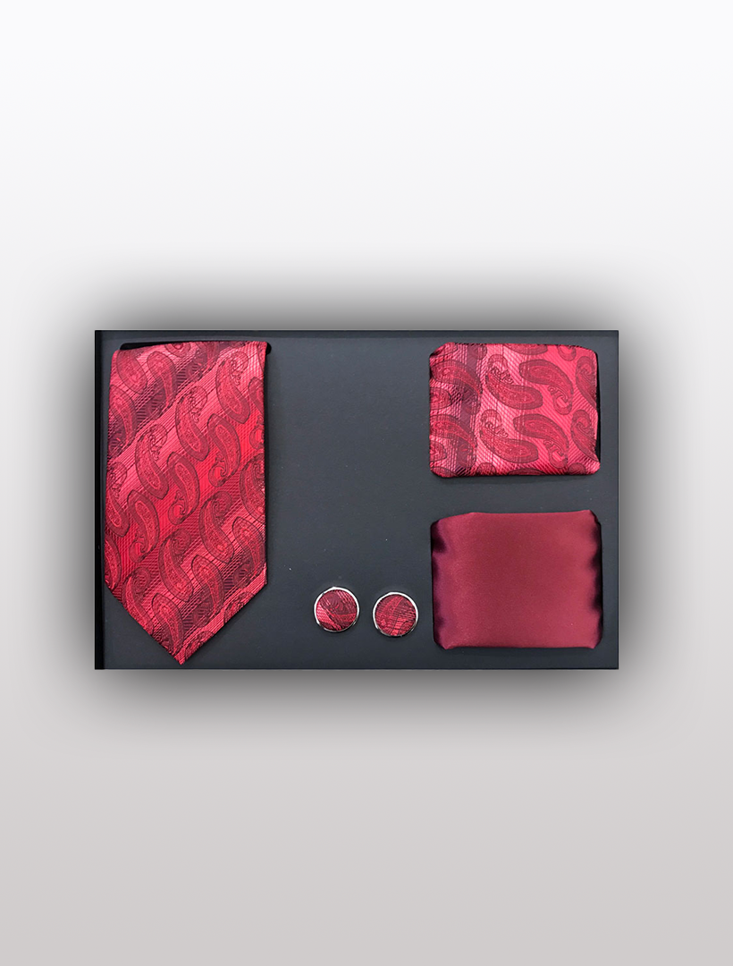 The Men's Four Piece Red Paisley Stripe Patterned Gift Box by Vesuvio Napoli includes an elegant red paisley tie, a matching pocket square, stylish cufflinks, and a plain red handkerchief, all artfully presented in a sophisticated black box.