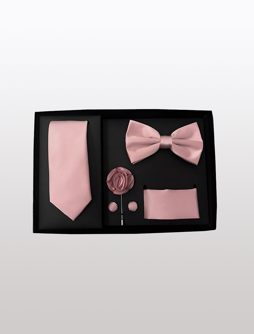 The Men's Five Piece Solid Dusty Pink Gift Box by Vesuvio Napoli features a collection of polyester accessories, including a tie, bow tie, flower pin, cufflinks, and pocket square. These items are elegantly packaged in a sleek gift box, perfect for adding sophistication to any formal event.