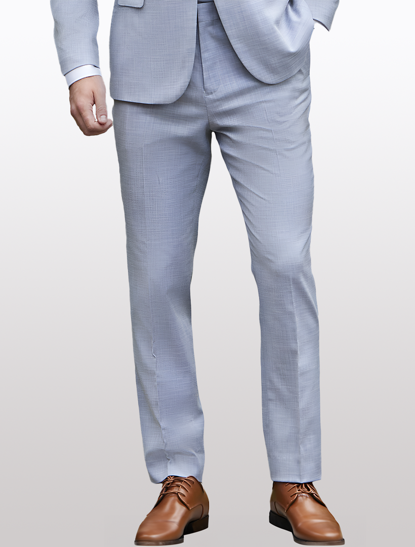 A person in Couture 1910's Men's Light Blue Dress Pants and brown shoes stands with one hand in their pocket against a plain background, exuding an effortless elegance suitable for any black-tie event.