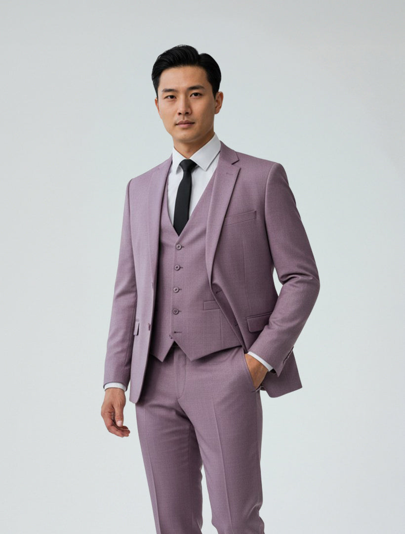 A man dressed in a Gino Vitale Men's Lilac Slim Fit Suit, paired with a white shirt and black tie, stands against a plain light background.
