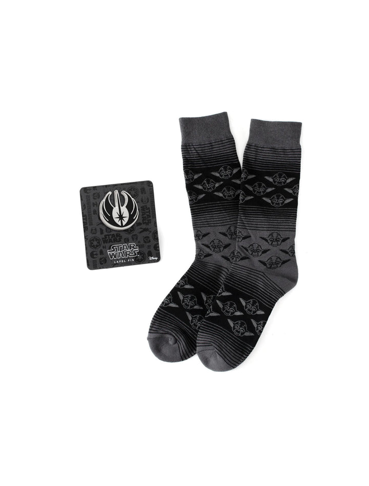 A pair of charcoal gray Yoda pattern crew socks and a Jedi crest lapel pin from the Star Wars Yoda Black Charcoal Dress Socks and Jedi Crest Lapel Pin Gift Set by Cufflinks.com on a display card.