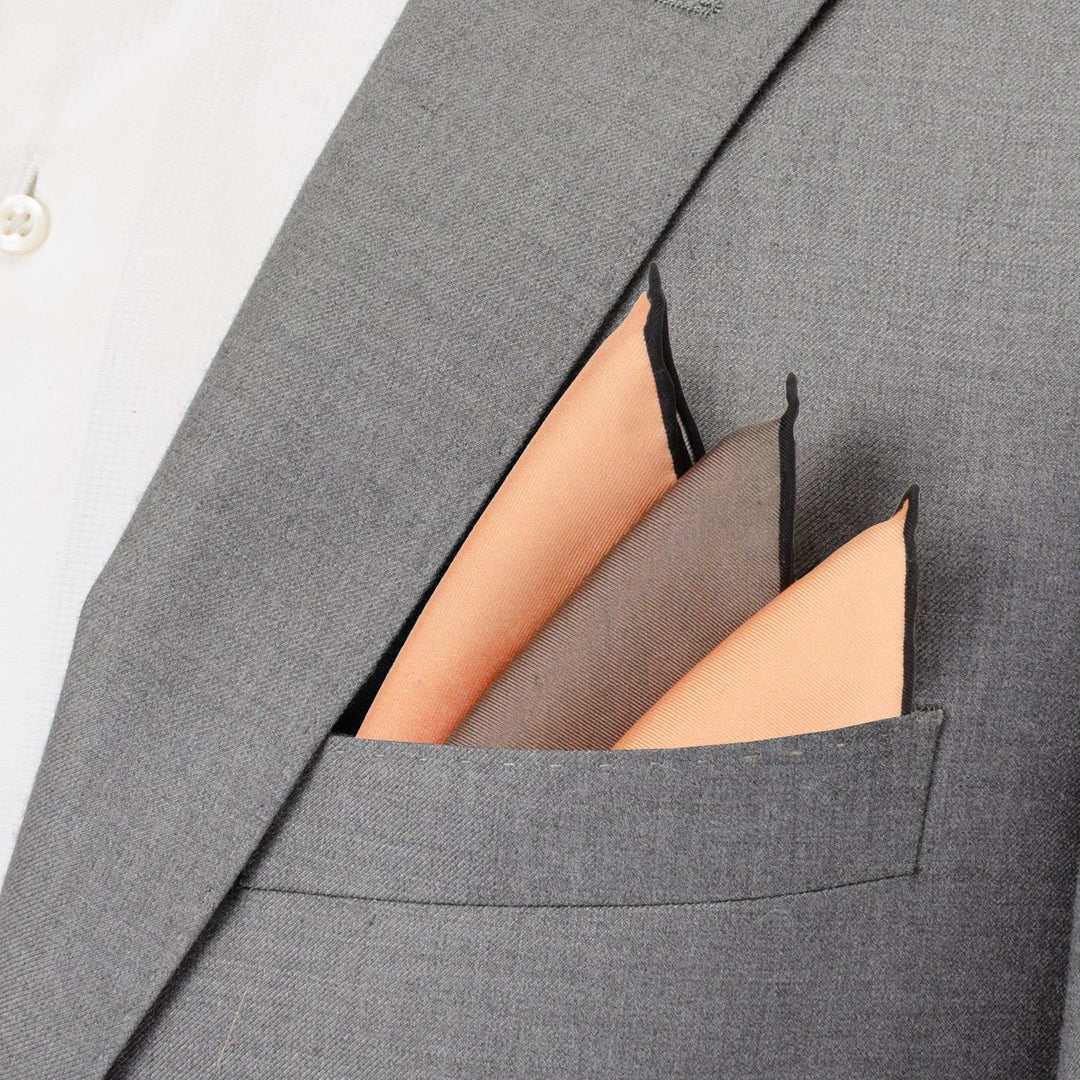 A grey suit pocket containing a Star Wars Tatooine Binary Sunset Pocket Square with orange and brown triple-pointed panels.