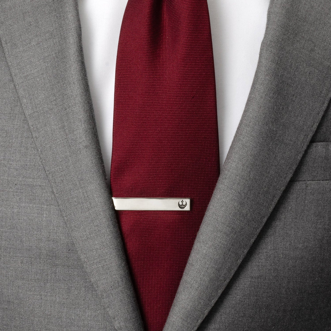 A silver Star Wars Rebel Alliance Starbird Crest Tie Bar attached to a dark red tie worn with a grey suit jacket.