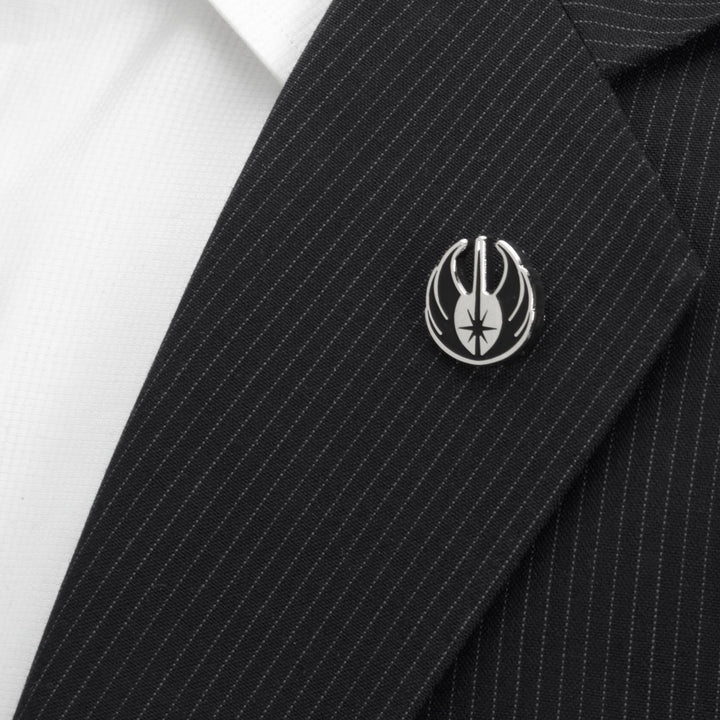 Silver Jedi symbol lapel pin from the Star Wars Obi-Wan Kenobi Blue LIGHTSABER Pattern Black Dress Socks with Jedi Crest Lapel Pin Gift Set attached to a pinstriped black suit jacket lapel.