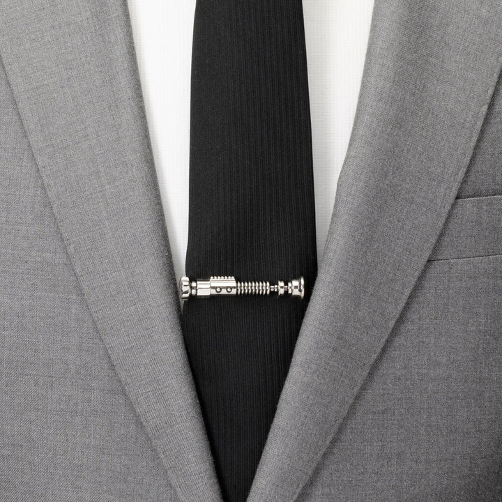 Silver-tone Star Wars Obi-Wan Kenobi Tie Clip on a black necktie worn with a grey suit jacket.