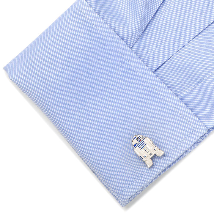 A light blue striped dress shirt cuff fastened with a silver Star Wars R2-D2 Cufflinks enamel cufflink.