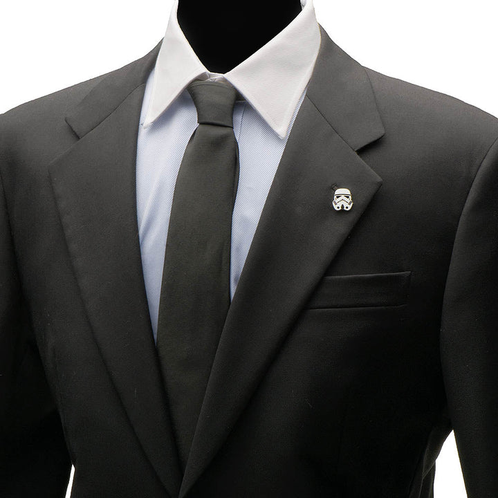 A silver Star Wars Stormtrooper Lapel Pin on the black suit jacket of a man wearing a light blue dress shirt and a black tie.