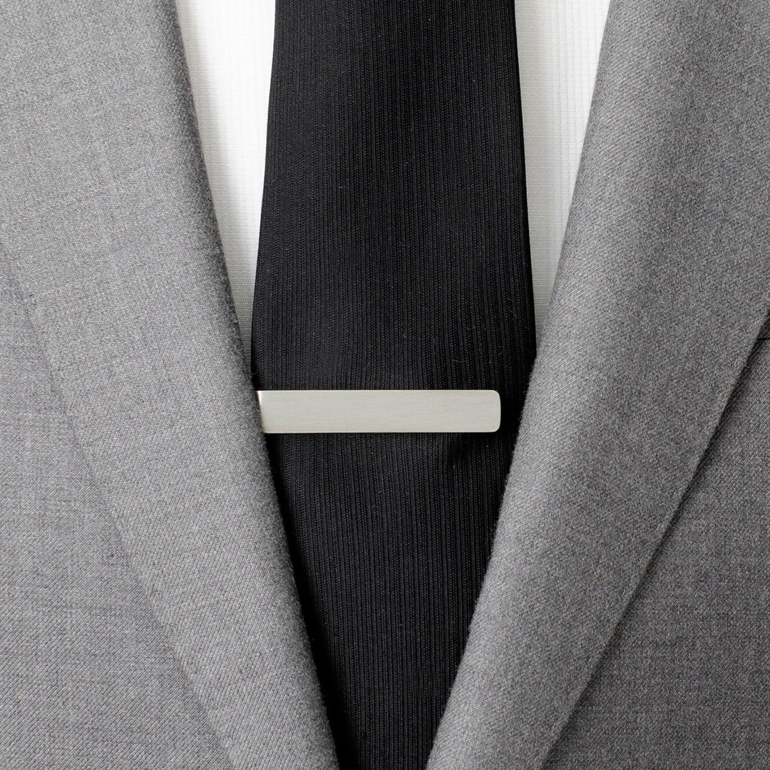 A Star Wars Princess Leia and Han Solo “I Love You / I Know” Hidden Message Tie Bar worn on a black tie over a white shirt and gray suit jacket.