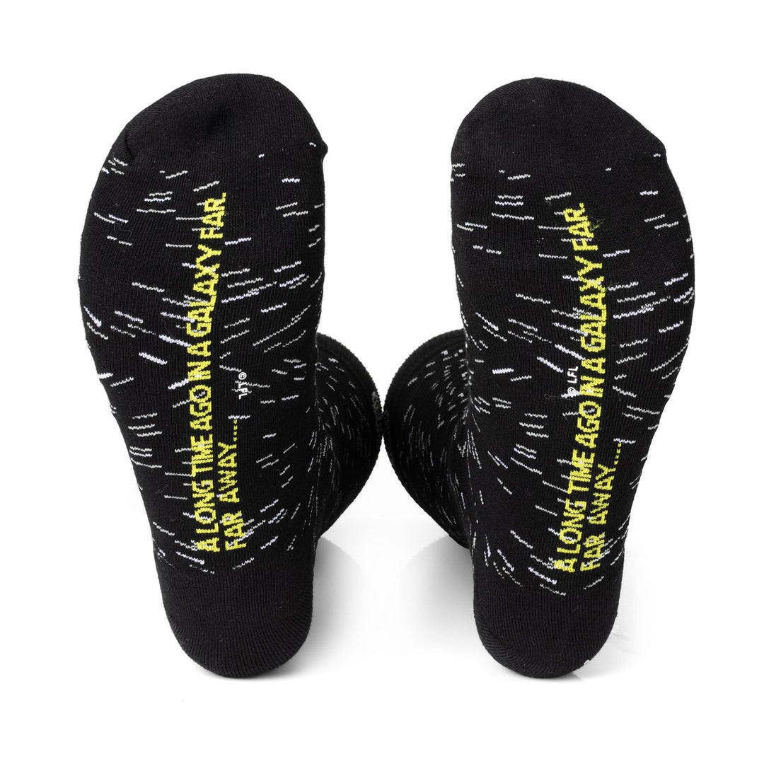 Two black Star Wars Transport 3 Pack Sock &amp; Lapel Pin Gift Set socks featuring white dashes and the yellow text “A long time ago in a galaxy far, far away...” printed on the soles.