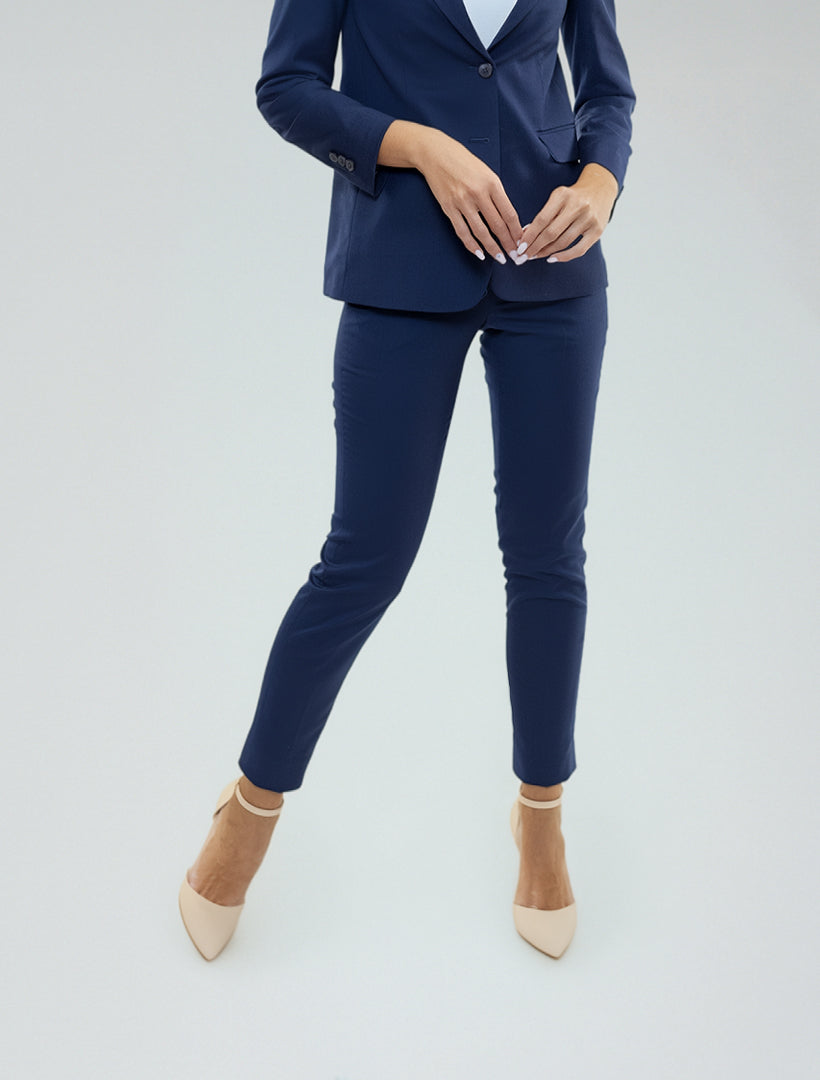 A person wearing Couture 1910 Women's Navy Suit Separates Pants and beige heels stands against a plain light background.