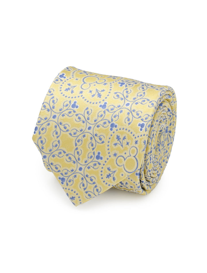 A Disney Mickey Mouse Yellow Multi Men’s Tie rolled into a coil with a blue scrolling vine pattern featuring Mickey Mouse head silhouettes.