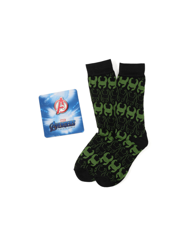 A pair of black Loki socks with a green horned helmet pattern next to a square Avengers logo card, part of a Marvel Avengers Loki Pattern Green and Black Gift Set by Cufflinks.com.
