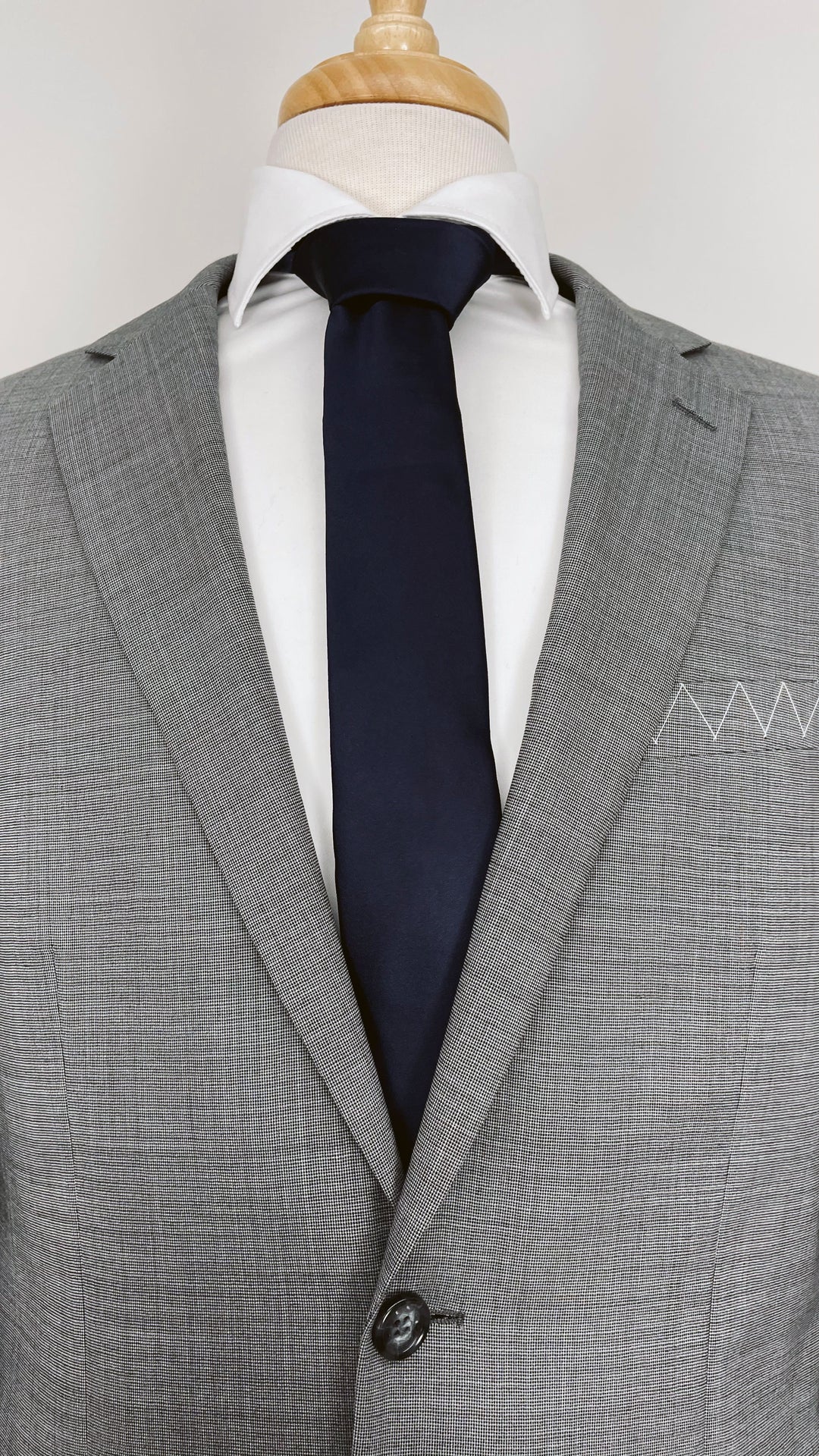 A mannequin dressed in a Karako Suits grey suit and complementing it with a Karako Collecti navy men&