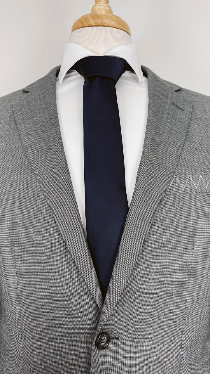A mannequin dressed in a Karako Suits grey suit and complementing it with a Karako Collecti navy men&