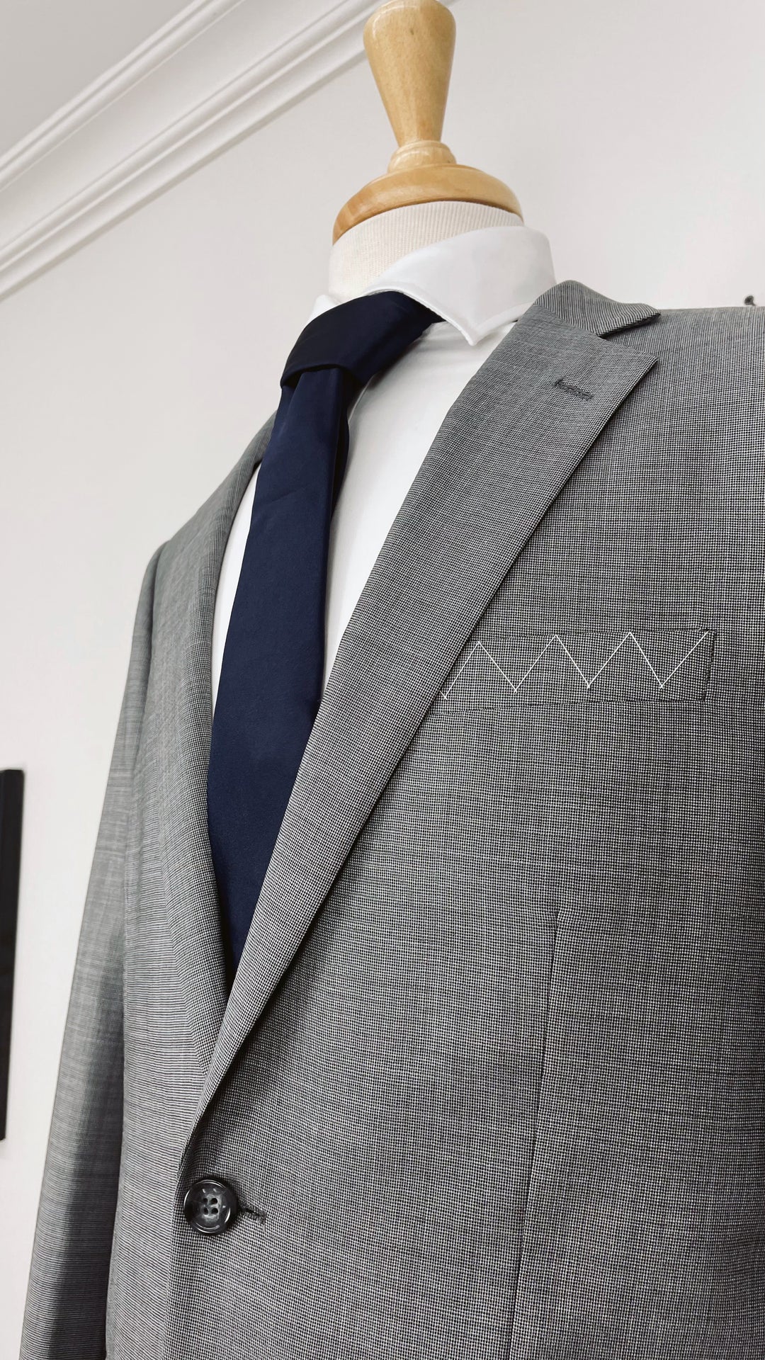 A Karako Collecti grey suit on a mannequin with a Navy Men&