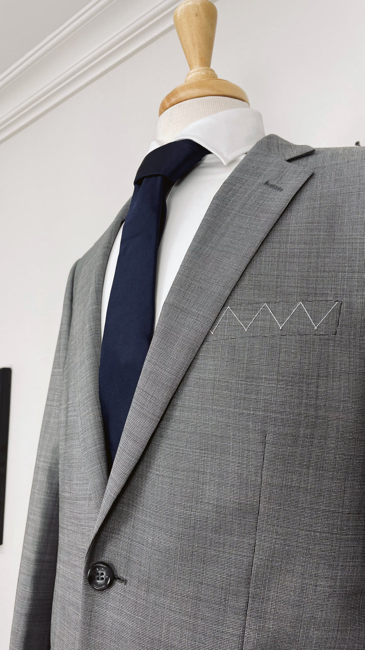 A Karako Collecti grey suit on a mannequin with a Navy Men&