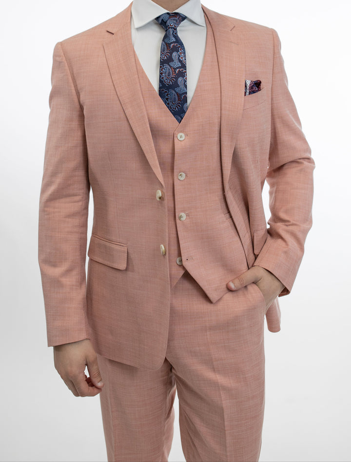 A man is posing in a Fubu The Colle slim fit pink suit, emanating both comfort and style.